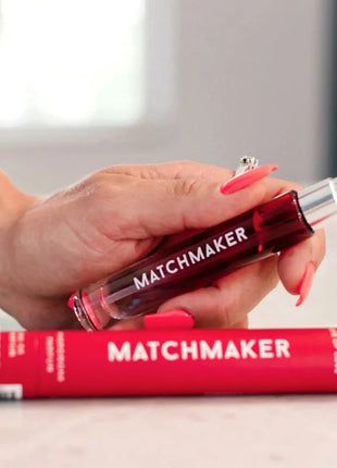 Eine transparente rote roll-on glasflasche mit silberkappe und matchmaker schriftzug für auge der liebe pheromon parfum