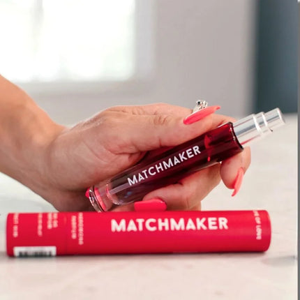 Eine transparente rote roll-on glasflasche mit silberkappe und matchmaker schriftzug für auge der liebe pheromon parfum