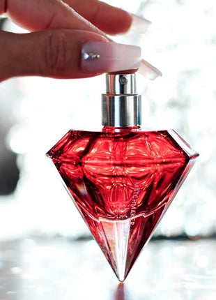 Ein leuchtend rotes, diamantförmiges parfumfläschchen auge der liebe matchmaker mit silberner spraydüse 30 ml