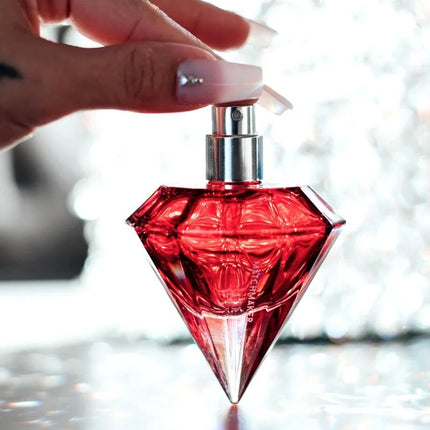 Ein leuchtend rotes, diamantförmiges parfumfläschchen auge der liebe matchmaker mit silberner spraydüse 30 ml