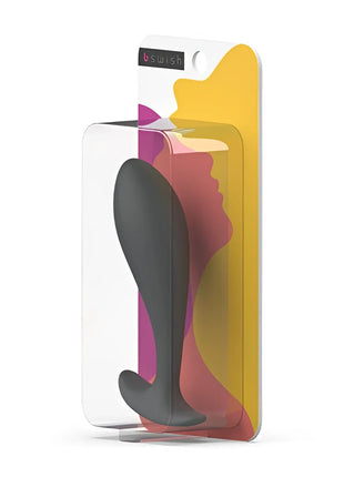 B swish bfille basic prostatic plug slate aus schwarzem silikon in transparenter verpackung mit buntem abstraktem hintergrund