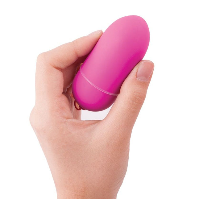 Eine vibrant pinke, glattoberfläche eiförmige vibrator von b swish bnaughty unleashed klassische rosa fernbedienung in hand gehalten