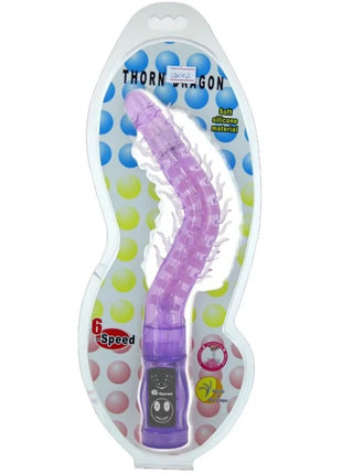 Lila silikon vibrator in drachenform mit strukturierter, segmentierter oberfläche und lächelndem gesicht am baum von baile thorn flieder stimulator vibrator