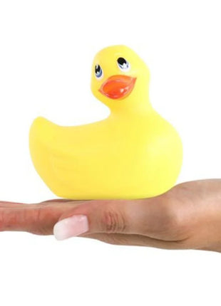 Ein klassische gelbe vibrierende Gummiente von Big Tease Toys mit schwarzen Augen und oranger Schnabel in einer Hand