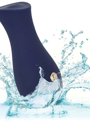 Dunkelblauer siliconvibrator mit goldenem knopfdruck auf gebogenem körper im wasser spritzend von calexotics