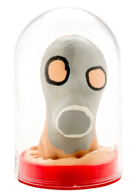 Graue cartoonartige gasmaske mit orangen augen und weißem mund, handbemalt, unter glaskuppel auf rotem sockel