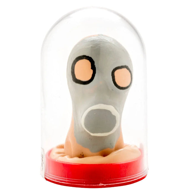 Graue cartoonartige gasmaske mit orangen augen und weißem mund, handbemalt, unter glaskuppel auf rotem sockel