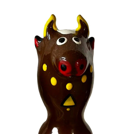 Glänzende braune keramik bullfigur mit gelben hörnern roter nase und dekorativen gelben punkten für condomerie kondome