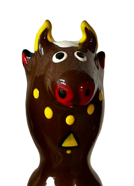 Glänzende braune keramik bullfigur mit gelben hörnern roter nase und dekorativen gelben punkten für condomerie kondome