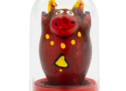 Ein glänzender roter bullfigur mit gelben hörnern und dekorativen akzenten unter einer klaren glaskuppel