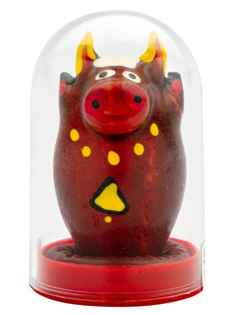 Ein glänzender roter bullfigur mit gelben hörnern und dekorativen akzenten unter einer klaren glaskuppel