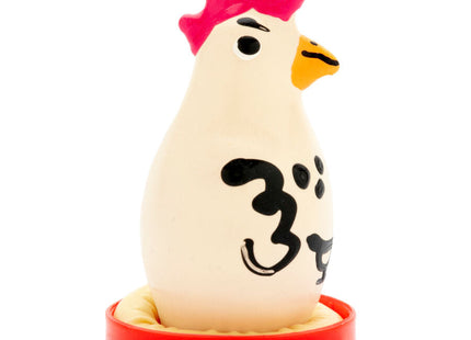 Ein weißer plastik-hühnerfigur mit pinkem kamm gelbem schnabel und schwarzen japanischen zeichen auf rotem sockel