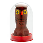 Eine braune schokoladeneulenfigur mit gelben augen und schwarzer gesichtszeichnung in einer klaren glaskuppel von condomerie