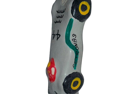 Graue keramik autofigur mit schwarzen und gelben rädern, grünen akzenten, rotem detail und petronas schriftzug, condomerie f1 mercedes xl