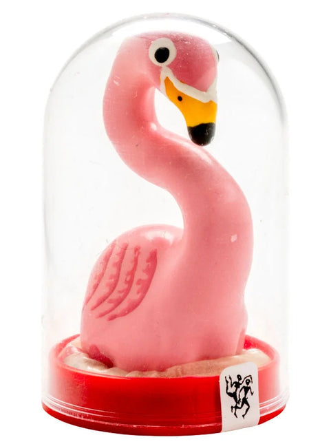 Eine pinke plastik flamingo figurine mit gelbem und schwarzem schnabel in einer klaren glaskuppel auf rotem sockel