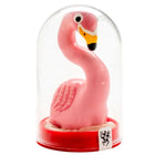Eine pinke plastik flamingo figurine mit gelbem und schwarzem schnabel in einer klaren glaskuppel auf rotem sockel