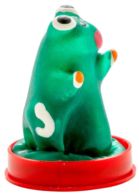 Grüne plastikfigur mit weißen und orangefarbenen akzenten auf rotem rundem sockel kondommodell frosch