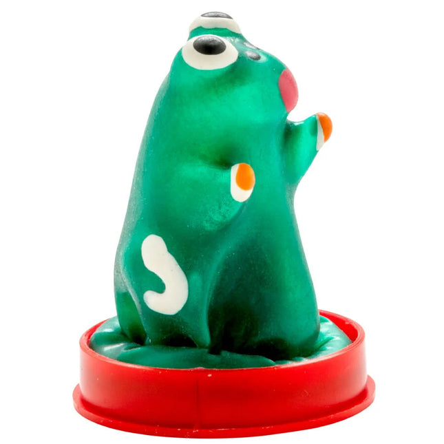 Grüne plastikfigur mit weißen und orangefarbenen akzenten auf rotem rundem sockel kondommodell frosch