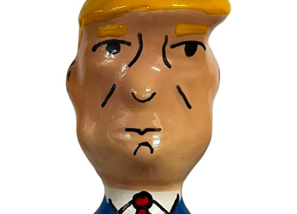 Ein glänzendes keramikfigürchen mit stylisiertem männlichen kopf, blonden haaren, blauem anzug und roter krawatte aus condomerie handbemalte neuheitskondome grumpy trump xl