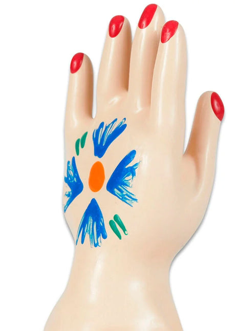 Beiges plastik-handmodell mit rotem nagellack und blumenmuster in blau orange und grün auf der handfläche