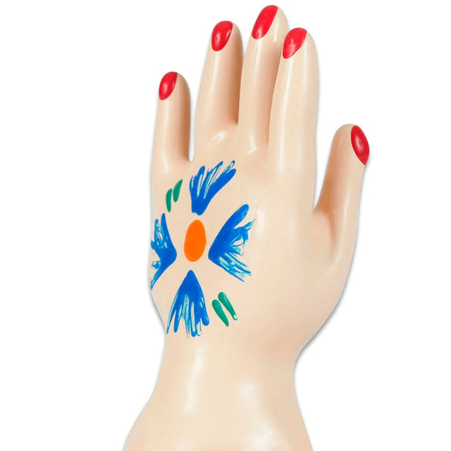 Beiges plastik-handmodell mit rotem nagellack und blumenmuster in blau orange und grün auf der handfläche
