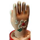 Beige plastik-handfigur mit hellgrüner nagellack und weißen, grünen sowie roten verzierungen auf der handfläche