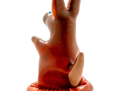 Braune keramik-kaninchenfigur mit aufrechten ohren und kleinem blauen punkt auf dem kopf in passender runder basis