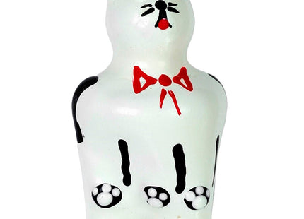 Weiße keramik katzenfigur mit schwarzen akzenten rosa ohren und nase roter schleife und pfotenabdrücken auf dem bauch