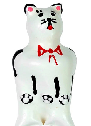 Weiße keramik katzenfigur mit schwarzen akzenten rosa ohren und nase roter schleife und pfotenabdrücken auf dem bauch