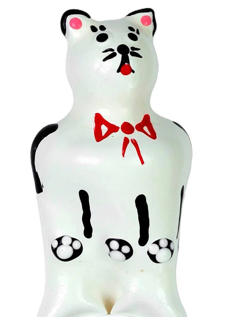 Weiße keramik katzenfigur mit schwarzen akzenten rosa ohren und nase roter schleife und pfotenabdrücken auf dem bauch