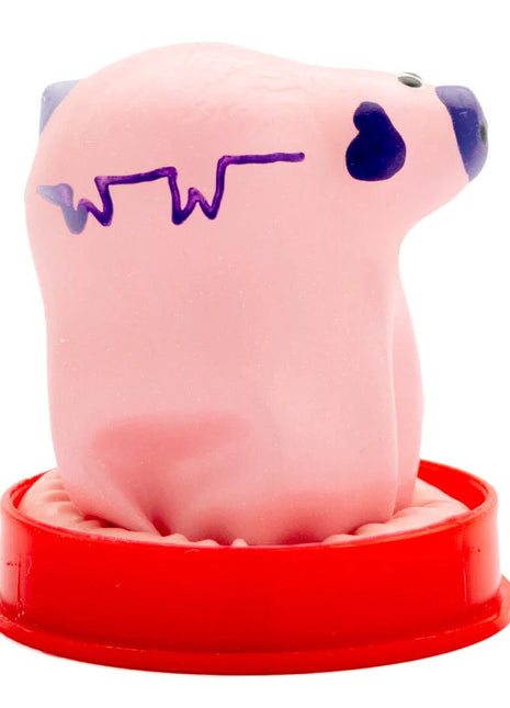 Pink stressball in schweineform mit lila linie und schwarzem herz auf rotem plastiksockel von condomerie