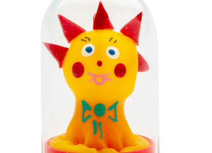 Eine gelbe plastikfigur mit roten spitzen und blauen augen in einer klaren glaskuppel auf rotem sockel von condomerie handbemalte neuheitskondome komet