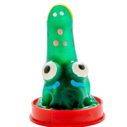 Grünes glänzendes plastikspielzeug mit pinken punkten und großen weißen augen auf rotem runder basis kondommodell kroko