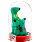 Eine grüne, gefleckte dinosaurierfigur mit gelben markierungen und schwarzen augen in einer klaren glaskuppel auf rotem sockel aus der condomerie handbemalte neuheitskondome loch ness monster serie