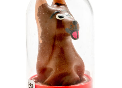 Eine braune schokoladenhundfigur mit schwarzen augen und rosa zunge unter einer klaren glaskuppel auf rotem ständer