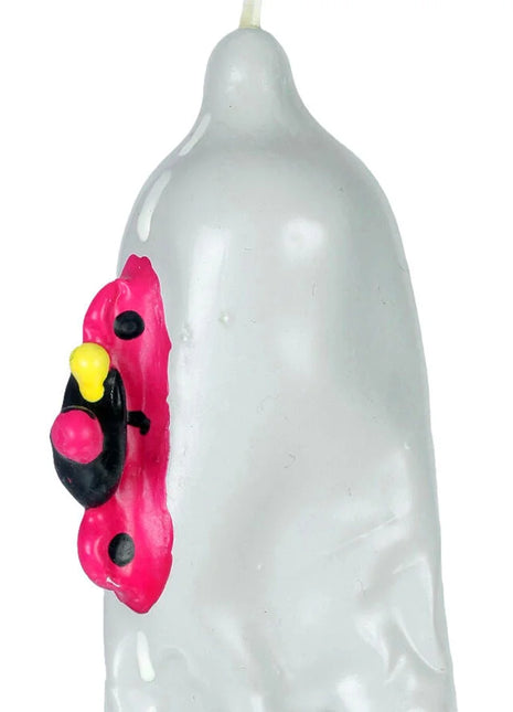 Translucente weiße kerze in kondomform mit handbemaltem pink-schwarz-gelbem cartoonmotiv bei condomerie motorrad xl