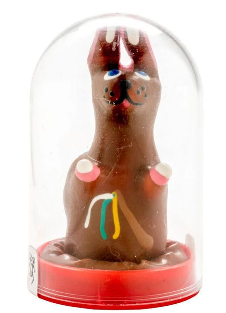 Eine handbemalte kondom-osterhase aus schokolade mit blauen augen und bunten details unter glasdom