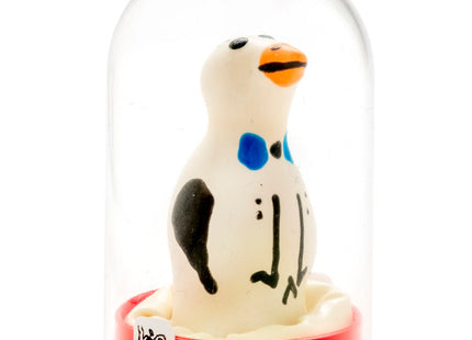 Ein charmantes weißes pinguinfigürchen mit schwarzen und blauen markierungen und oranger schnabel in einer glaskuppel auf rotem sockel aus der serie condomerie handbemalte neuheitskondome pinguin