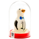 Ein charmantes weißes pinguinfigürchen mit schwarzen und blauen markierungen und oranger schnabel in einer glaskuppel auf rotem sockel aus der serie condomerie handbemalte neuheitskondome pinguin