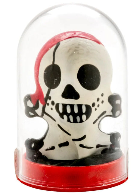 Weiße piratenschädel-figur mit schwarzen augenklappen und zähnen in rotem bandana im glaskuppelgehäuse auf rotem sockel