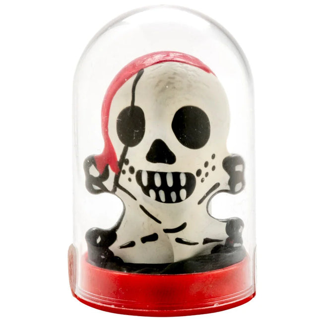 Weiße piratenschädel-figur mit schwarzen augenklappen und zähnen in rotem bandana im glaskuppelgehäuse auf rotem sockel