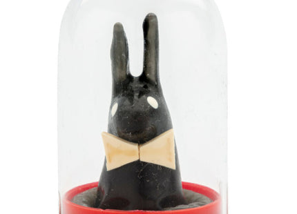 Schwarze hasenfigur mit weißen augen und beigem schleifenband unter glaskuppel auf rotem sockel von condomerie spielzeug kondome