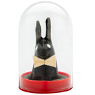 Schwarze hasenfigur mit weißen augen und beigem schleifenband unter glaskuppel auf rotem sockel von condomerie spielzeug kondome