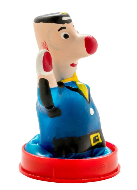 Bunte plastikfigur eines cartoon-charakters mit roter nase schwarzem haar und blauer latzhose auf rotem sockel kondome polizist