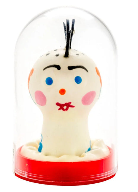 Eine handbemalte weiße keramikfigur mit blauen augen und roter schleife in glasdom auf rotem sockel von condomerie punk