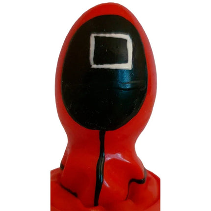 Rote plastikfigur einer figur im kapuzenanzug mit schwarzem gesicht und weißem quadrat als handbemalter condomerie kondom