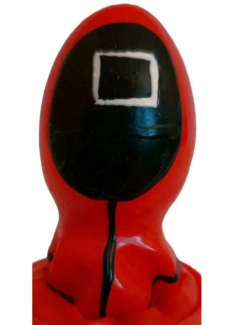 Rote plastikfigur einer figur im kapuzenanzug mit schwarzem gesicht und weißem quadrat als handbemalter condomerie kondom