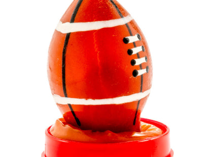 Eine glänzende orangefarbene rugbyballförmige kerze auf rotem kunststoffständer von condomerie handbemalt