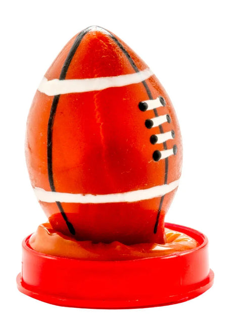 Eine glänzende orangefarbene rugbyballförmige kerze auf rotem kunststoffständer von condomerie handbemalt