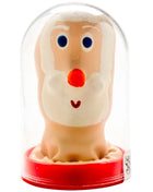 Eine fröhliche beige santa claus figur aus glas mit weißem bart und roter nase auf rotem sockel im condomerie kondom